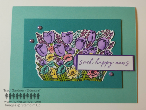 Aqua colored card with a focal image of purple, blue, pink and yellow flowers, with the sentiment, Such Happy News