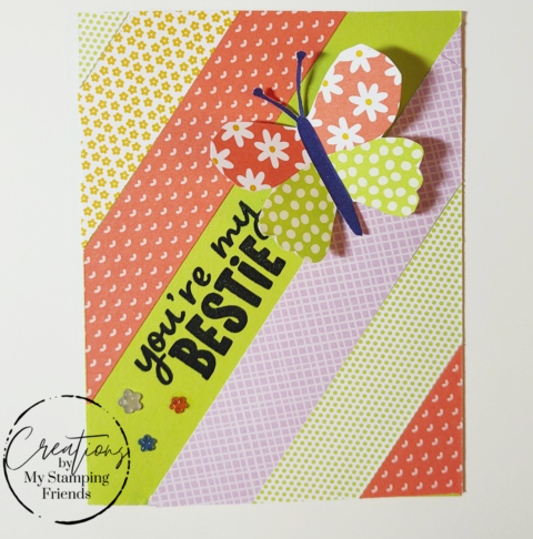 Greeting card showing diagonal stripes of patterned paper that features small flowers, grid lines, and dots. The card shows a floating butterfly in matching paper, with the sentiment, You’re My Bestie