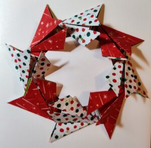 Folded Christmas paper in a round pattern, with a white circle in the middle to fake the hole in the center of the wreath.