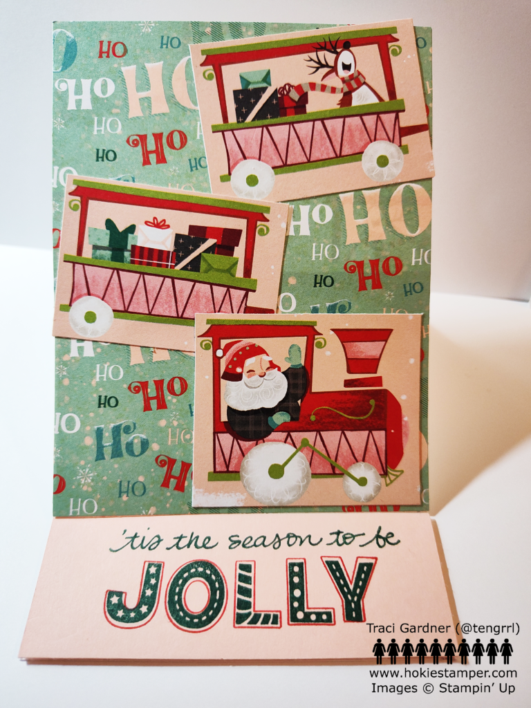 Easel Christmas card showing patterned paper with the words Ho Ho Ho in the background and images of Santa in a train engine, a train car with presents, and a train car with presents and a singing reindeer.